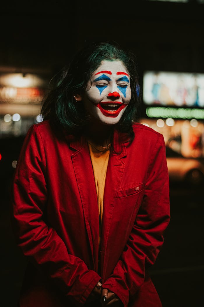 Colorful clown portrait with bold makeup and costume outdoors at night, showcasing vivid facial expressions.